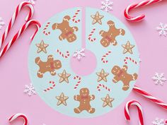 a paper plate decorated with gingerbreads and candy canes on a pink background