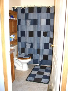 a bathroom with a checkered shower curtain, toilet and rug in the floor area