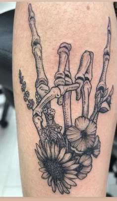 the back of a woman's shoulder with flowers and skeleton bones on her arm