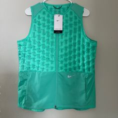 Elevate Your Activewear Game With This Nike Therma-Fit Adv Down Running Vest. The Sleeveless Jacket In A Gorgeous Shade Of Green Is Perfect For Fall Or Spring And Is Made Of Softshell Fabric With A 100% Polyester Lining. The Vest Features A Full Zip Closure, Pockets, And Reflective Detailing, Making It Perfect For Gym And Training, Walking, Or Running And Jogging. This Nike Dri-Fit Vest Has A Regular Fit And Is Available In Size L. The Outer Shell Material Is Polyester, And The Insulation Materi Sporty Green Vest For Spring, Green Sporty Vest For Sports, Green Sporty Workout Vest, Sporty Green Workout Vest, Green Sportswear Outerwear For Workout, Green Athleisure Outerwear For Workout, Nike Green Athleisure Outerwear, Softshell Fabric, Running Nike