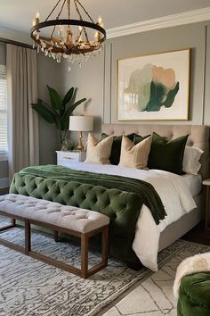 a bedroom with a large bed, green velvet upholstered chair and chandelier