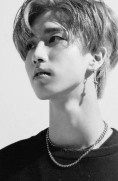 black and white photograph of a woman with short hair wearing a t - shirt, necklace and earrings