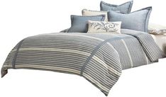 a bed covered in blue and white striped comforter sets with pillows on top of it