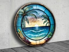 a round stained glass window with palm trees and the ocean on it's side