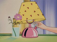 a pink lamp sitting on top of a table next to a vase filled with flowers