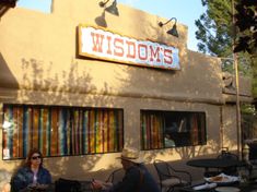 two people sitting at tables outside of a restaurant with the word wisconsin's on it