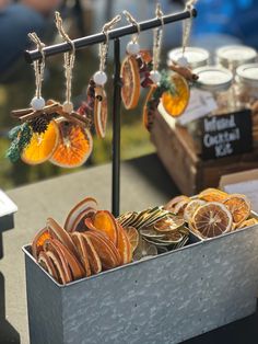 an assortment of oranges are on display in a metal container with earrings hanging from them