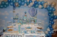 a table topped with blue and white balloons