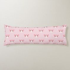 a pink rectangular pillow with bear faces on it, against a light gray wall background