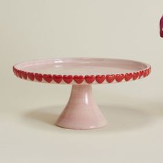 a pink cake plate with red hearts on it and a vase in the back ground