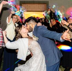 a bride and groom kissing on the dance floor at their wedding reception with sparklers in the air