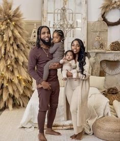 a man, woman and child standing in front of a christmas tree