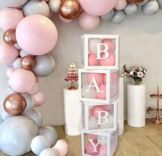 a baby shower is decorated with balloons and pink, silver, and gold letters on the wall