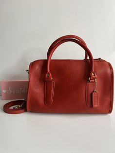 Original Vtg Coach Classic Large Madison with strap Red leather with brass hardware Inside is roomy with a slip pocket secured with a top zipper  Measures: 11"L, 8"H, 4 1/2"W Strap drop: 7" Removable 40" strap  Made in New York, USA  #250-7709 Cleaned, conditioned and ready to wear! Flaws: large mark near top, pen mark near top and a few minor marks noticeable upon close inspection Questions? Just ask More great finds available g81 Coach Vintage Handbags, Top Questions, Vintage Satchel, Vintage Coach Bags, Hip Style, Top Handle Bags, Vintage Coach, Vintage Handbags, Coach Purses