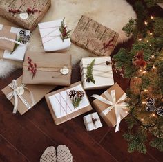 several wrapped presents sitting on the floor next to a christmas tree with pine cones and berries