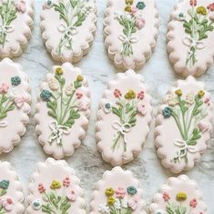 many decorated cookies with flowers on them sitting on a counter top next to each other