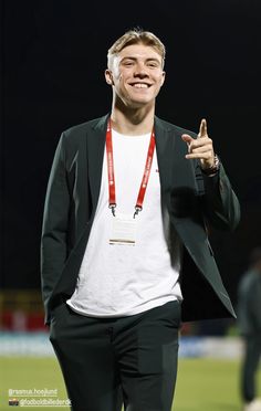 a man wearing a white t - shirt and black suit jacket giving the peace sign