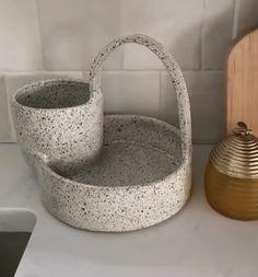 two white baskets sitting on top of a counter next to a golden vase and wooden stand