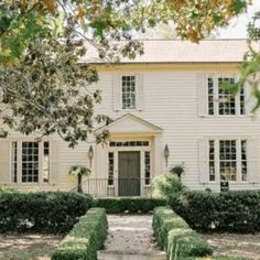 a white house with hedges in front of it