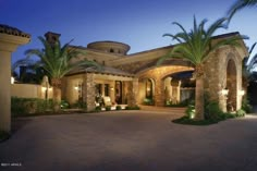 a large house with palm trees and lights on the front entrance to it at night