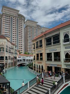 people are walking around in the middle of an outdoor shopping area with water and buildings