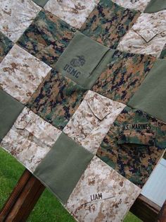 a close up of a patchwork quilt on a wooden bench with grass in the background