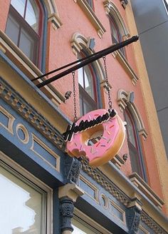 a pink donut hanging from the side of a building