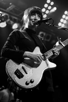 a young man playing an electric guitar in front of a microphone on stage at a concert