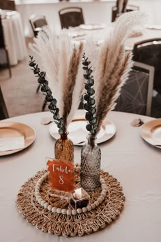 there are two vases with flowers in them on top of a round table cloth