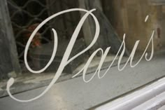 the word paris is etched into an old window