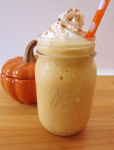 a glass jar filled with whipped cream next to an orange pumpkin