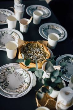 a table topped with plates and cups filled with food