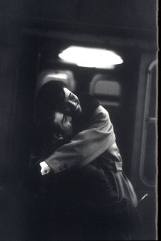 a black and white photo of a person sitting on a train