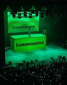 a man standing on top of a green box in front of a crowd at a concert