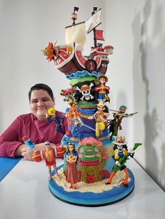 a woman sitting in front of a large cake with pirate figures on it's side