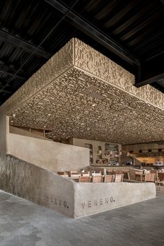 the inside of a restaurant with tables and chairs under a wooden structure that has words written on it