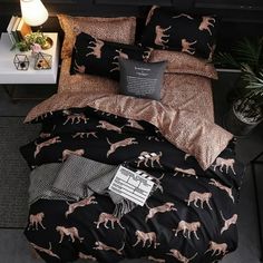 a bed with black and gold sheets, pillows and blankets on top of the bed