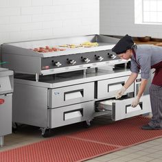 a man in an industrial kitchen preparing food on top of stoves and ovens