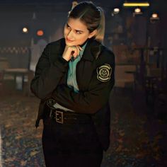 a woman dressed in police uniform posing for the camera with her hand on her chin