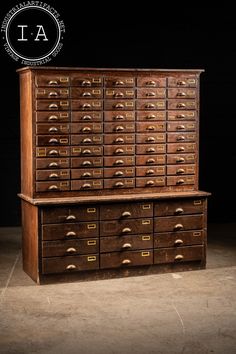 an old wooden filing cabinet with many drawers on the top and bottom, in front of a black background