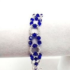 a bracelet with blue beads and charms on it's side, sitting on a white surface