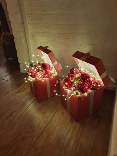 two red boxes with christmas lights on them are sitting on the floor next to each other