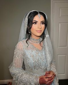 a woman in a wedding dress and veil posing for the camera with her hands on her chest