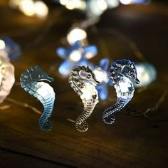 three seahorses sitting on top of a wooden table next to some string lights