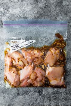 raw chicken in a plastic bag sitting on top of a cement surface with a tag attached to it