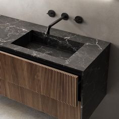 a bathroom vanity with a marble sink and black faucet on the wall above it