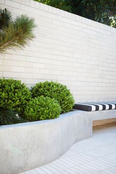 two large planters sitting next to each other near a white brick wall with black and white stripes on it