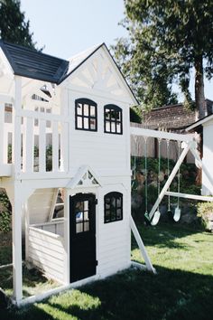 there is a white house with a slide in the back yard and a play set behind it