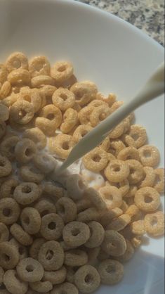 a bowl full of cereal with a spoon sticking out of the top in front of it