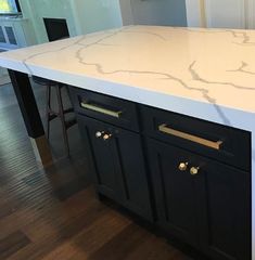 a kitchen island with marble top and black cabinets